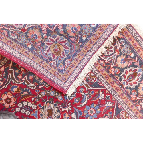 1184 - A vintage Kashan hand knotted wool carpet with central medallion design and blue borders on a red fi... 