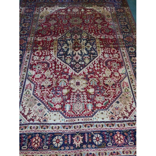 1198 - A red ground Persian Tabriz carpet with a traditional design and blue ground border, 118