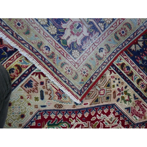 1198 - A red ground Persian Tabriz carpet with a traditional design and blue ground border, 118