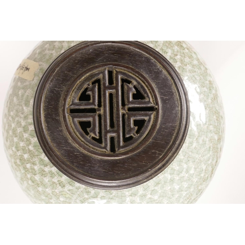 23 - A Chinese green glazed crackleware jar with a turned wood cover, the body with raised auspicious sym... 