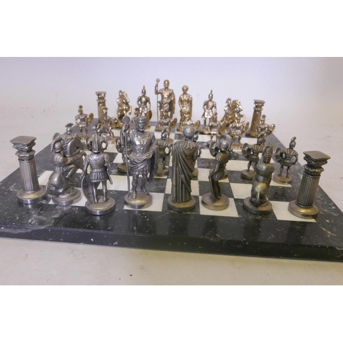 31 - A gilt and white metal chess set, the figures cast as classical Romans, on a marble board, 16