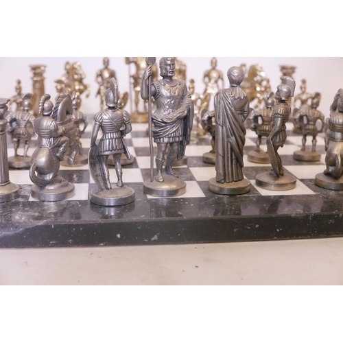 31 - A gilt and white metal chess set, the figures cast as classical Romans, on a marble board, 16