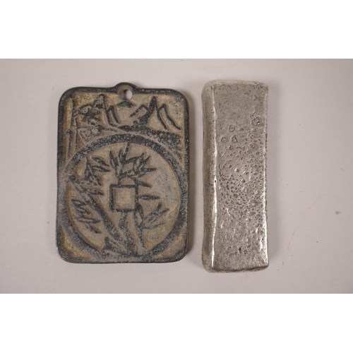 48 - A Chinese white metal ingot, together with a bronze token with character inscription decoration, lar... 