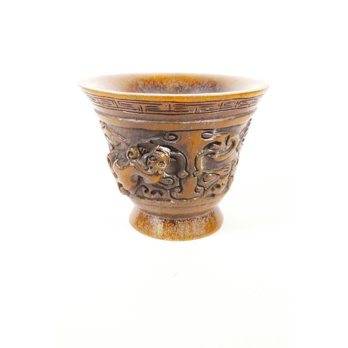 18 - A Chinese faux horn libation cup with two carved handles in the form of kylin, impressed mark to bas... 