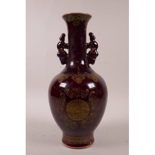 60 - A Chinese burgundy glazed porcelain vase with two handles and gilt decoration of auspicious symbols,... 