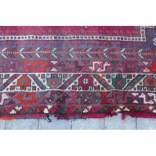 1115 - A Persian red ground carpet with geometric pattern, edges frayed, 71