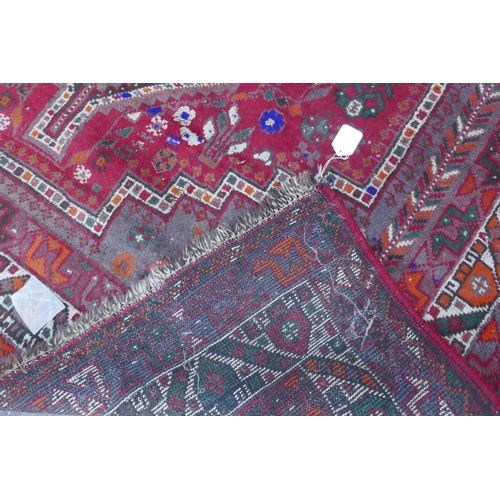 1115 - A Persian red ground carpet with geometric pattern, edges frayed, 71