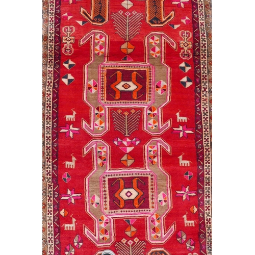 1126 - A Persian wool runner with a geometric medallion design on a rich red field, 52