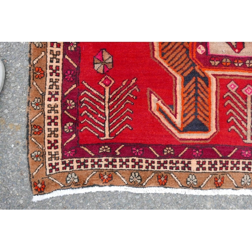 1126 - A Persian wool runner with a geometric medallion design on a rich red field, 52