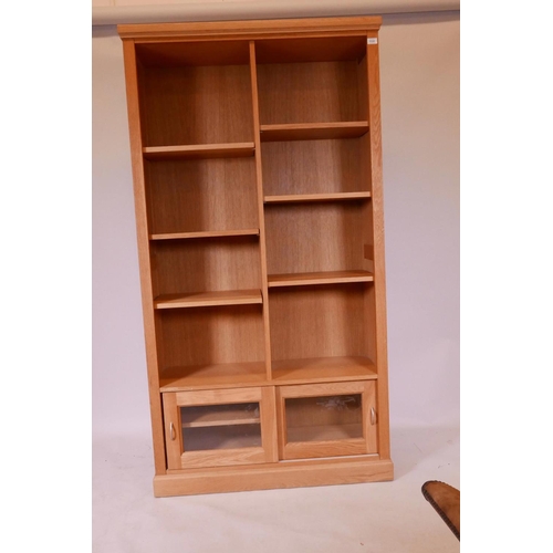 1112 - A John Lewis light oak open bookcase, with adjustable shelves over two glazed cupboards, 40