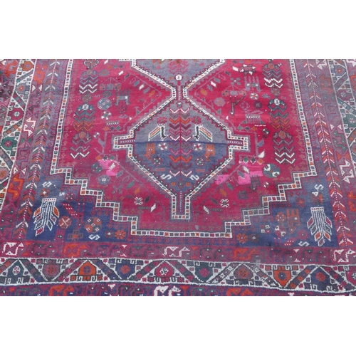 1115 - A Persian red ground carpet with geometric pattern, edges frayed, 71