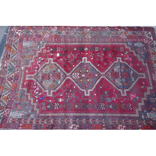 1115 - A Persian red ground carpet with geometric pattern, edges frayed, 71