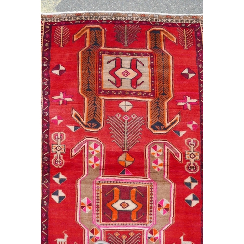 1126 - A Persian wool runner with a geometric medallion design on a rich red field, 52