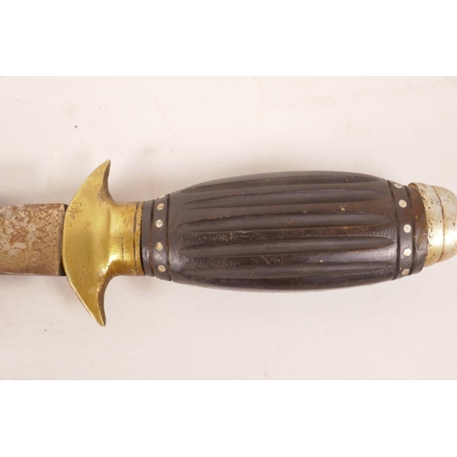 194 - An ethnic ceremonial dagger with engraved blade, carved wood handle and brass fittings, 13