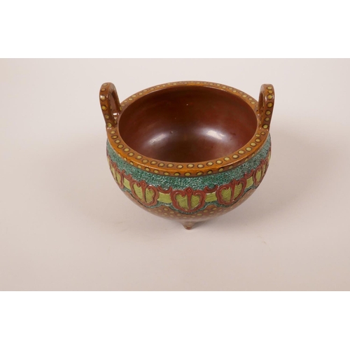 228 - A Chinese redware pottery censer with two handles raised on tripod feet with raised and enamelled ar... 