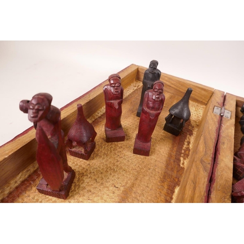 452 - An African carved wood chess set in a carved and dyed box, 15