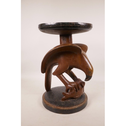 453 - An African carved wood stool in the form of an eagle catching a fish, 13½