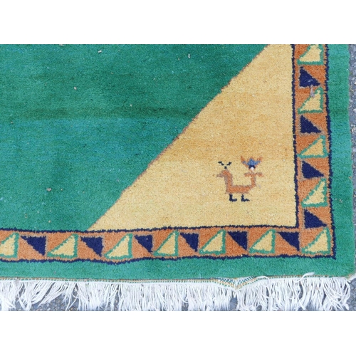 1134 - An Indian hand woven deep pile wool carpet with stylised bird decoration on a green field, 72