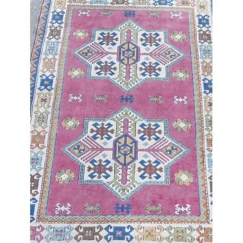 1135 - A Middle Eastern hand knotted wool carpet with star patterns on a terracotta field, 50