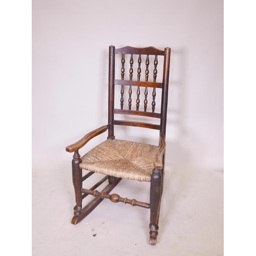 1140 - A C19th oak Lancashire spindle back rocking chair with a rush seat, 36½