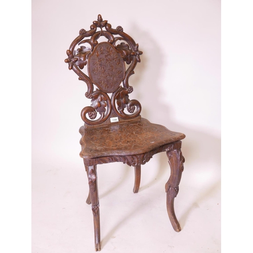 1141 - A C19th Black Forest musical chair with carved and pierced back, raised on cabriole supports