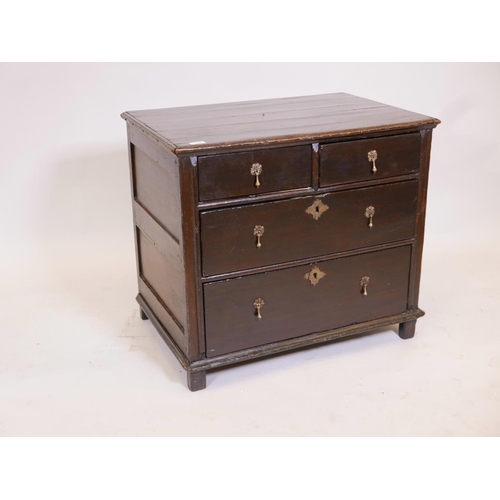 1102 - A Queen Anne oak chest of drawers, with panelled sides and plank top, and two over two drawers, rais... 