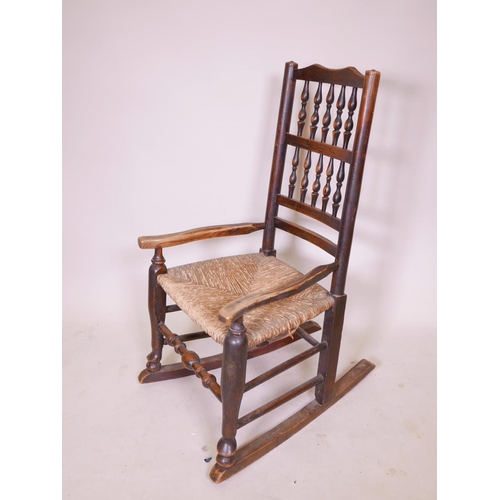 1140 - A C19th oak Lancashire spindle back rocking chair with a rush seat, 36½