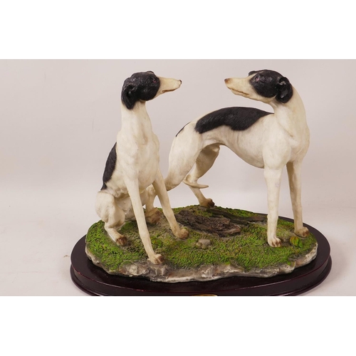 41 - A composition figure of two greyhounds on an oval wooden plinth, 8½