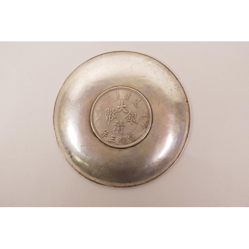 13 - A Chinese white metal coin dish with raised decoration of the emblems of the Eight Immortals, 3½