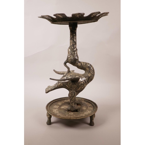 20 - A Chinese mixed metal candlestick stand in the form of a phoenix, decorated with scrolling patterns ... 