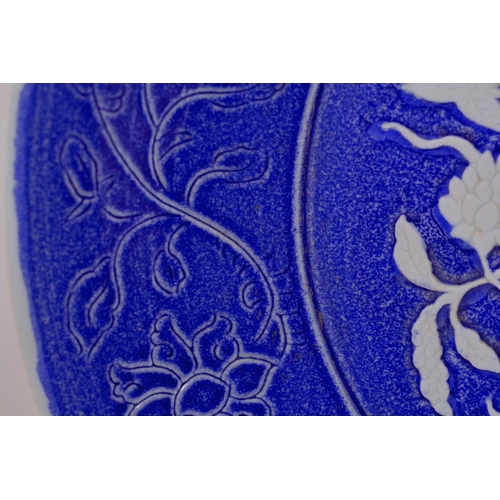 55 - A large Chinese blue and white pottery charger with raised and incised floral decoration, incised 4 ... 