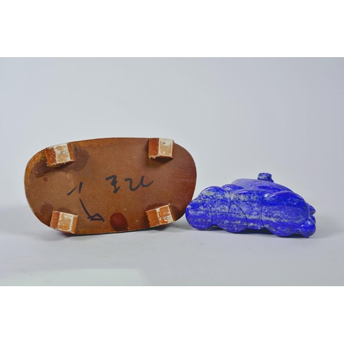 64 - A Chinese carved lapis ornament in the form of a kylin atop a money token, on a wood stand, 6