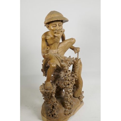 47 - An oriental carved wood figure of a fisherman with large fish, seated on a coral reef, 21