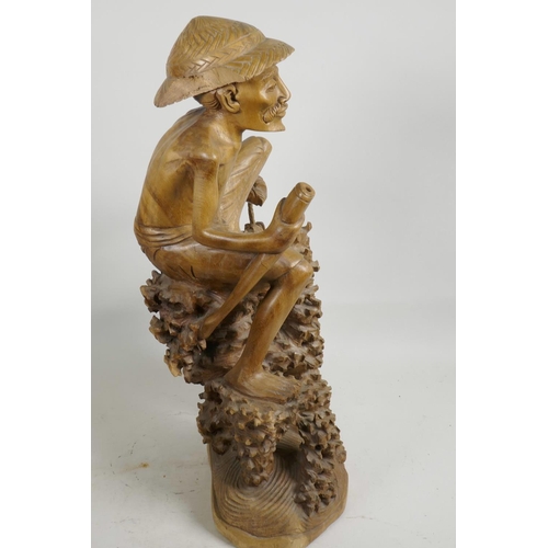 47 - An oriental carved wood figure of a fisherman with large fish, seated on a coral reef, 21