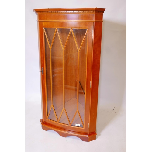 1824 - A bowfronted yew wood hanging corner cabinet with astragal glazed door, 22