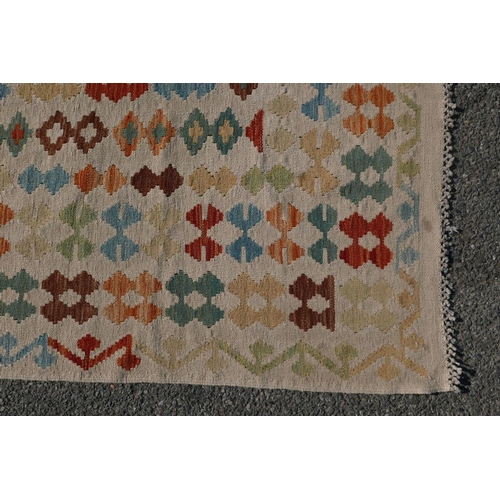 1828 - A Konya Kelim flatweave rug with geometric patterned decoration on a red field, with a deep cream bo... 