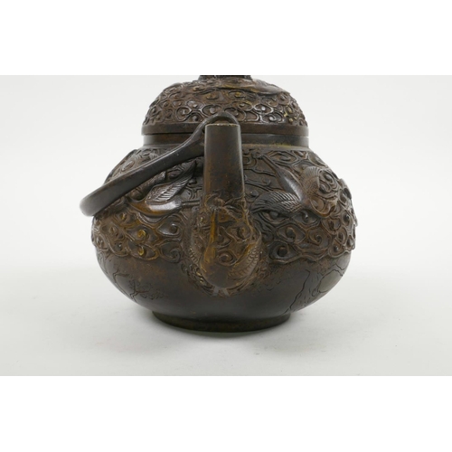 18 - A Chinese bronze teapot with raised decoration of cranes in flight, four character mark to base, 5½