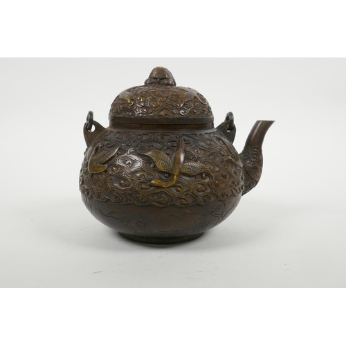 18 - A Chinese bronze teapot with raised decoration of cranes in flight, four character mark to base, 5½