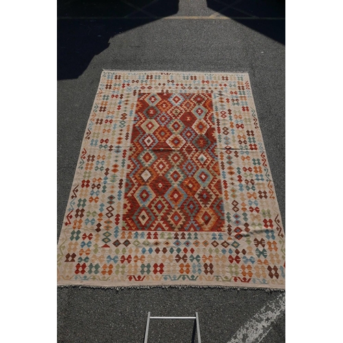 1828 - A Konya Kelim flatweave rug with geometric patterned decoration on a red field, with a deep cream bo... 