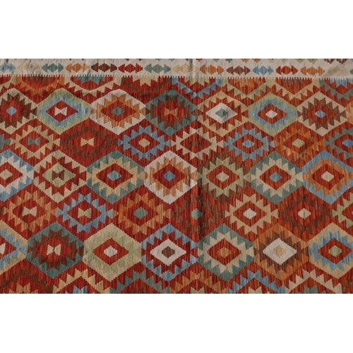 1828 - A Konya Kelim flatweave rug with geometric patterned decoration on a red field, with a deep cream bo... 