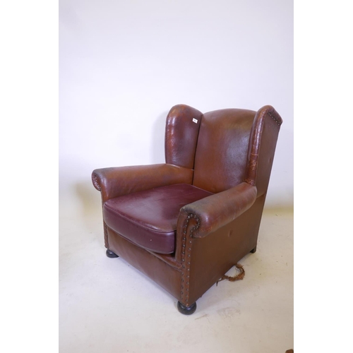 1831 - A brown leather wing back arm chair, with a vinyl seat cushion, 34