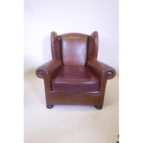 1831 - A brown leather wing back arm chair, with a vinyl seat cushion, 34