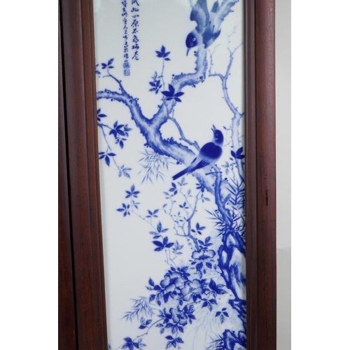 43 - A pair of Chinese blue and white porcelain panels in hardwood frames, decorated with birds amongst f... 