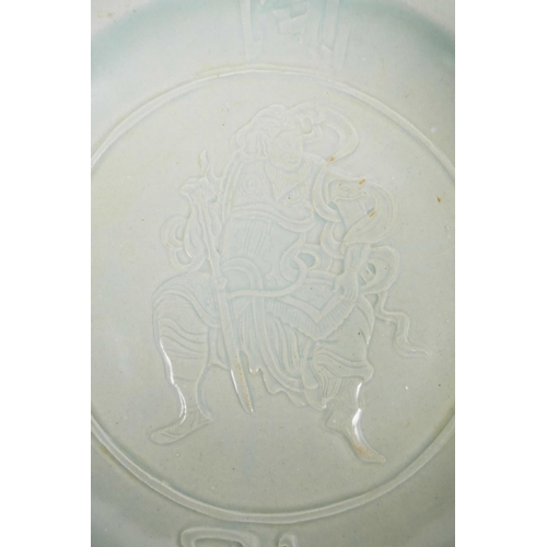 65 - A Chinese celadon glazed porcelain charger with incised decoration of a warrior and four auspicious ... 