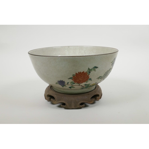 58 - A Chinese crackleware bowl with famille verte decoration of birds in a landscape, on a carved hardwo... 