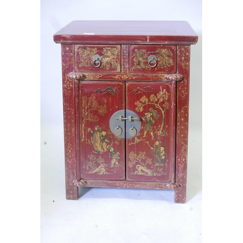 1169 - A Chinese red lacquered cabinet with two drawers over two cupboards and painted gilt decoration, 20