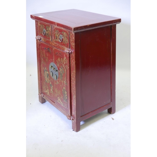 1169 - A Chinese red lacquered cabinet with two drawers over two cupboards and painted gilt decoration, 20