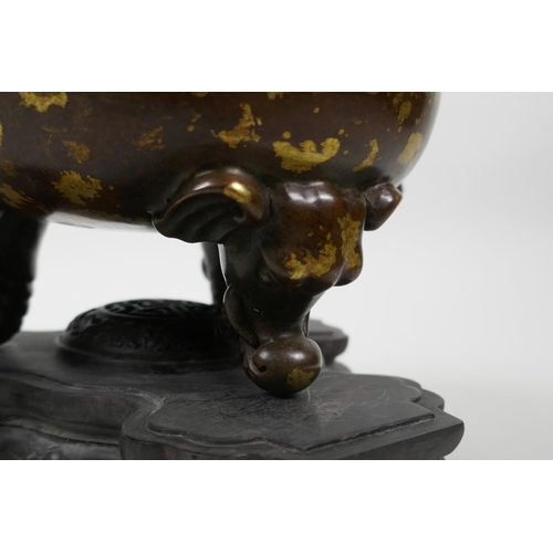 33 - A Chinese bronze censer and pierced cover on tripod supports, with two elephant mask handles and gil... 