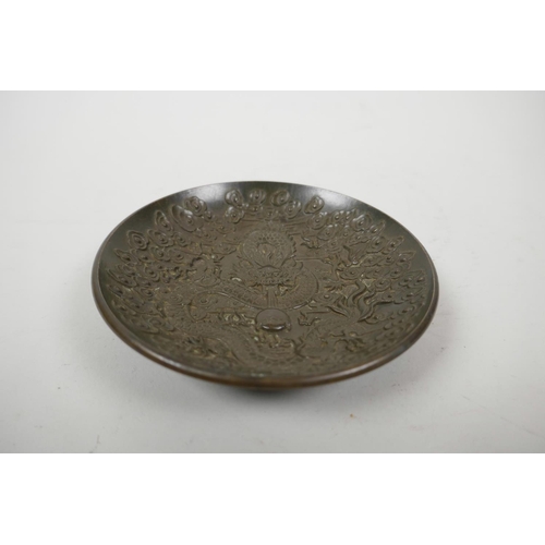 35 - A Chinese bronze trinket dish with raised decoration of a dragon chasing the flaming pearl, 4 charac... 