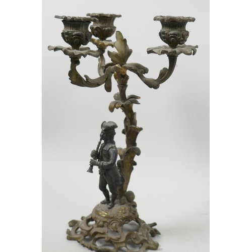 46 - A gilt metal three light table candelabra, the scrolling base with bronze figure of a musician stand... 